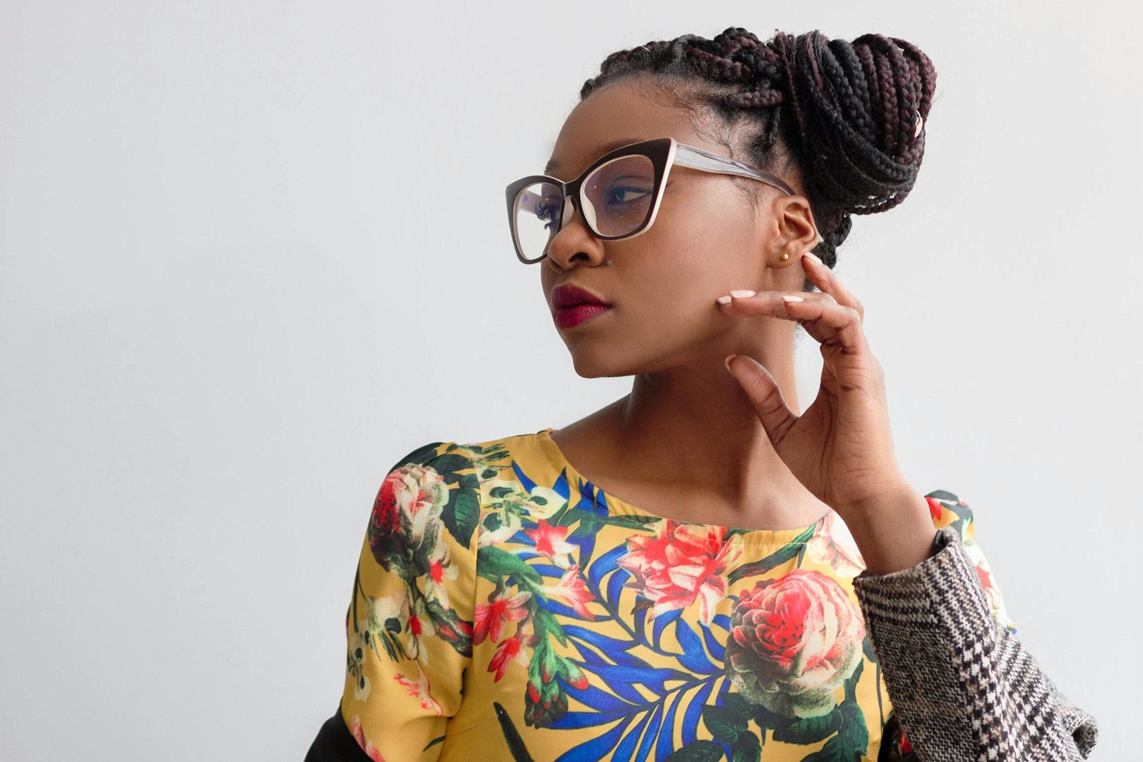 Elegant portrait featuring a woman in glasses with braided hairstyle and floral top.